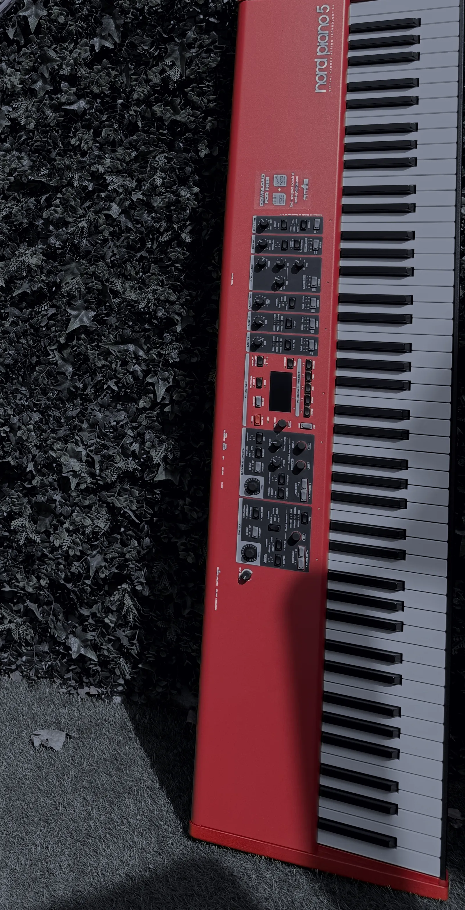 Le piano mis à disposition pour les ateliers, posé debout contre un mur végétal.